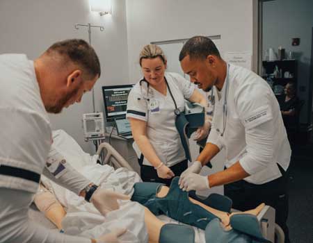 MGA nursing students place a leg brace on a training manikin during a lab class.